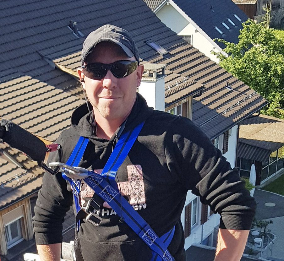 Pascal Diethelm mit Sicherheitsgurt auf einem Ziegeldach